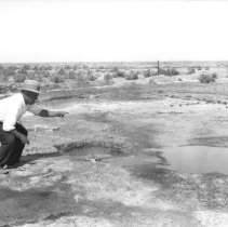 Man pointing to one of the mud pots located near the Salton Sea.