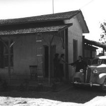 Virginia Hetzel shaking hands with two women standing on the porch of a hou