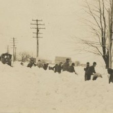 crew shoveling snowbound electric car