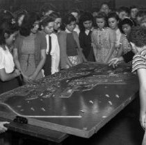 Hollenbeck Junior High School activities.  Teacher using model of Los Angeles harbor to point out places of interest to students who will soon take school excursion to the harbor as part of their study.  (Model made by W.P.A.) Model contains 18 samples of exports and 24 imports of the Los Angeles harbor.  Study print sets of harbor activities and a descriptive booklet accompany the model.