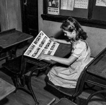 Bancroft junior high school activities.  Students working with and operating audio-visual tools.  Girl looking at page of small pictures.
