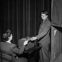 Consumer interest committee of the Los Angeles city defense council at North Hollywood high school.  A consumer casting a ballot.
