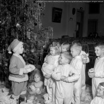 Christmas party, Cahuenga School.  Child dressed as Santa, distributing presents.