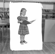 Elementary library activities, [Reading books].  Blocked out negative of girl standing reading a book. (Sherman Oaks School).