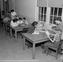 Pupils, teachers and student teachers in typical classroom situations.  Taken at Nora Sterry school. [Students reading with teachers.]
