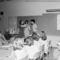 Class activities at Bellagio Road Elementary School.  Students and teachers are shown using the library facilities, music instruction, using audio visual equipment, playing musical instruments, and art.