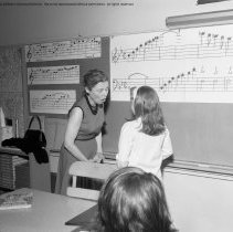 Class activities at Bellagio Road Elementary School.  Students and teachers are shown using the library facilities, music instruction, using audio visual equipment, playing musical instruments, and art.