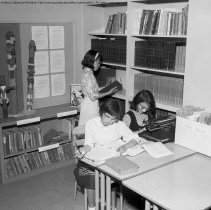 Class activities at Bellagio Road Elementary School.  Students and teachers are shown using the library facilities, music instruction, using audio visual equipment, playing musical instruments, and art.
