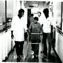 A young lady being assisted in the corridor.  See Voyage boards on walls.