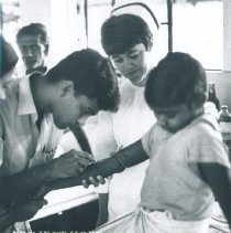 Grace Tucker observing a Lab Tech draw blood on the SS HOPE in Ceylon.