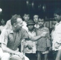 Ralph Bellamy chats with young Vietnamese while televising a documentary.