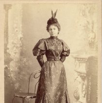 Studio portrait a woman posed next to a chair