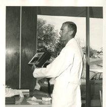 Price E. Thomas in white lab coat holding up anniversary gift 1969 Jun 16