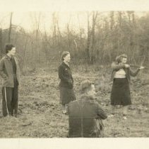Woman shooting gun in field with man and women ca. 1942