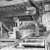Sawmill interior, man sawing log