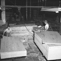 Mill interior, workers stacking plywood