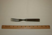 Fork with three long tines; it is made of pewter with a wooden handle.