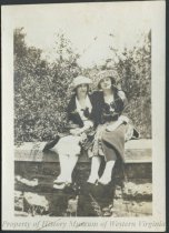 Two women sitting on wall