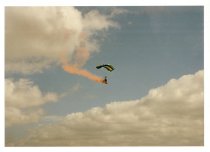 A parachuter with a red smoke trail
