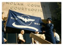 Two WASP holding up a flag in front of the Nolan County Courthouse
