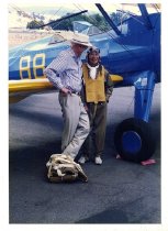 Maggie Gee and a man standing next to a biplane