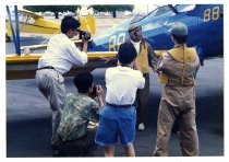 Maggie Gee in a flight suit being photographed next to a biplane