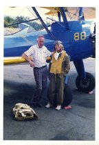 Maggie Gee and a man standing next to a biplane
