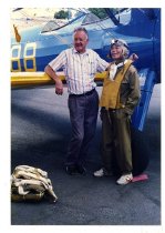 Maggie Gee and a man standing next to a biplane
