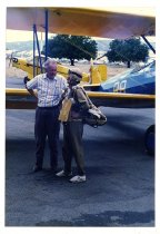 Maggie Gee and a man standing next to a biplane