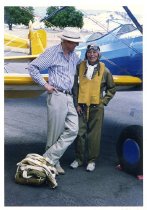 Maggie Gee and a man standing next to a biplane