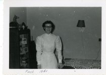 Jackline Myers in dental uniform standing in living room