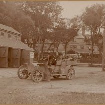 Three men in open car outside Farragut Hotel & Garage