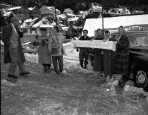 Young ladies with "We Have Been Helped" sign