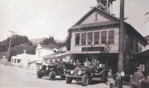 Firemen on fire trucks outside of station; early 1900s