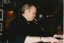 Sitting at keyboard, on stage at Sweetwater, smoking a cigarrette, during J