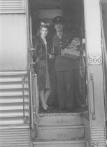 Military man and woman inside train entrance, unknown