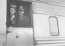 Military man and woman inside train entrance, unknown