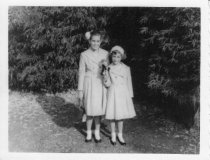 Carmel and Anita, two young girls standing out doors, Christmas 1957.