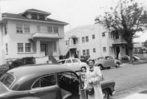 Woman getting into car with houses in background, unknown.
