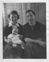 Cousin George and Mary holding baby inside house, unknown.