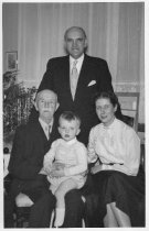 Three adults with child sitting on what appears to be grandfather's lap at