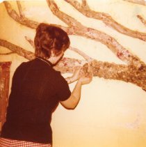Rita Ann Bert attaches paper-mache to branch