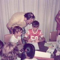 Robert Kopek leans down to assist a child