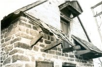 DeTurk House, view of damage to pent roof & outlookers (c.1974-1975)