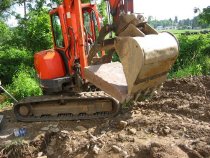 0052--L3 grappled with excavator bucket and "thumb" to its site.