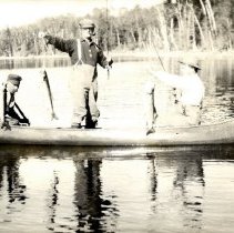 Three men in a canoe with fish