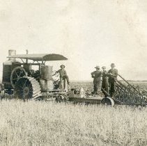 Unidentified men on a tractor and farm equipment