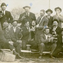 Group of 13 men holding glasses of beer