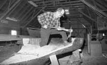 William Rollins shaping his log canoe with an adze