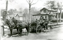 Carriage with a man near two horses and four passengers in carriage